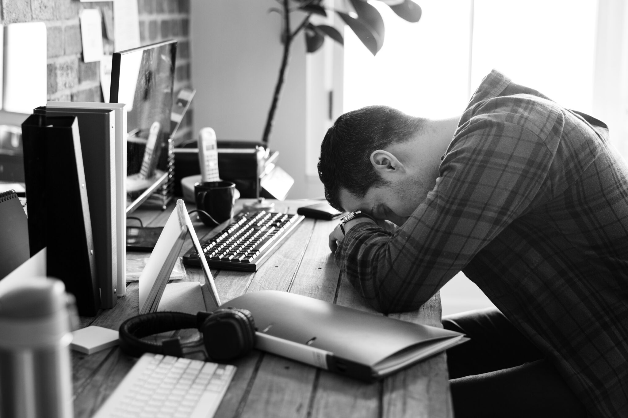Un homme tête baissée sur son bureau, épuisé.