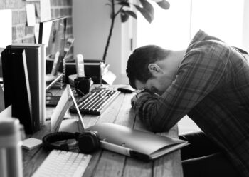 Un homme tête baissée sur son bureau, épuisé.