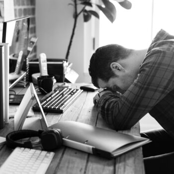 Un homme tête baissée sur son bureau, épuisé.