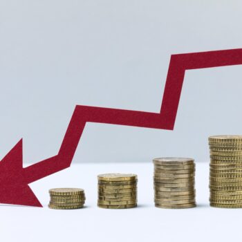 baisse de moyens : flèche descendante et différents tas de pièces qui diminuent