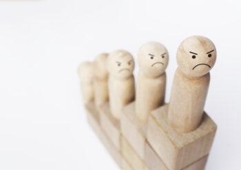 Gros plan sur une figurine en bois symbolisant des personnes mécontentes sur une ascension de blocs de bois formant un graphique de croissance.