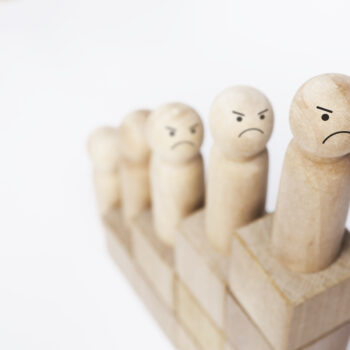 Gros plan sur une figurine en bois symbolisant des personnes mécontentes sur une ascension de blocs de bois formant un graphique de croissance.