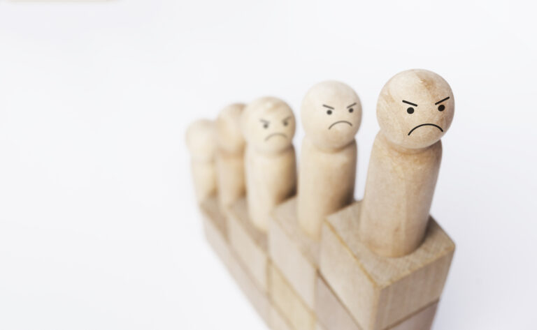 Gros plan sur une figurine en bois symbolisant des personnes mécontentes sur une ascension de blocs de bois formant un graphique de croissance.